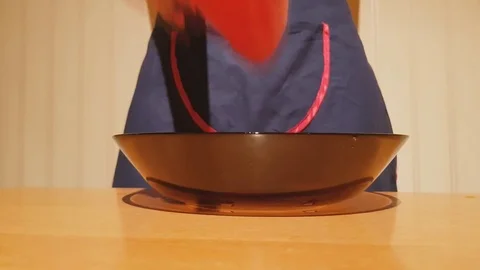 Chef in apron putting fresh red peppers on plate in home kitchen, cooking salad Stock Footage 82323872