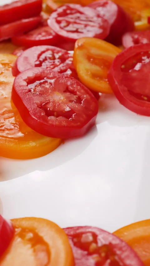Chef arranges fresh yellow and red tomato slices on a white plate. 库存影片 341476903