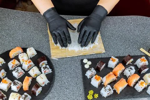 The chef arranges rice for sushi roll on a bamboo mat. Stock Photos