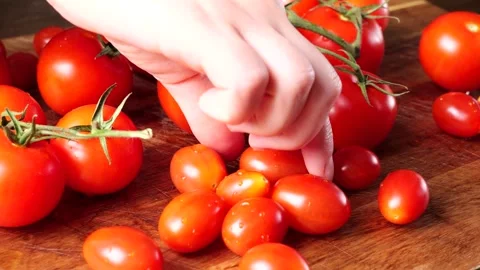 Chef arranging cherry and vine tomatoes on wooden cutting board Stock Footage 305808537