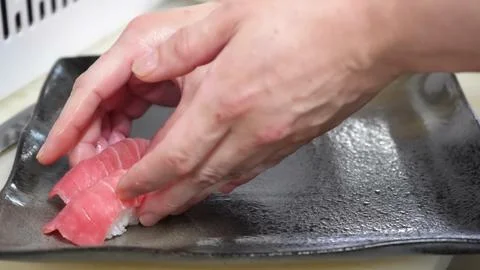 Chef arranging fresh assorted sushi nigiri pieces on a dark plate Stock Photos