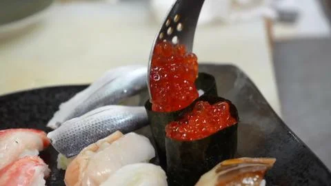 Chef arranging fresh assorted sushi nigiri pieces on a dark plate Stock Photos