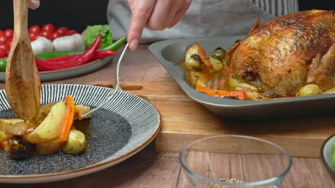 A chef is arranging roasted chicken and vegetables into a serving plate in 4k. Stock Footage 145118468