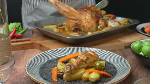 A chef is arranging roasted chicken and vegetables into a serving plate in 4k. Stock Footage 145118724