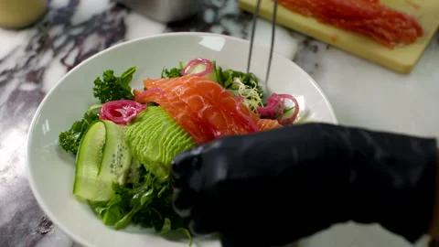 Chef Arranging Salmon and Avocado Salad in Bowl on Marble Kitchen Countertop Stock Footage 337652980