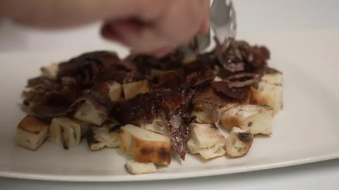 Chef arranging sliced doner meat over pide bread for an iskender kebab Stock Footage 333531287