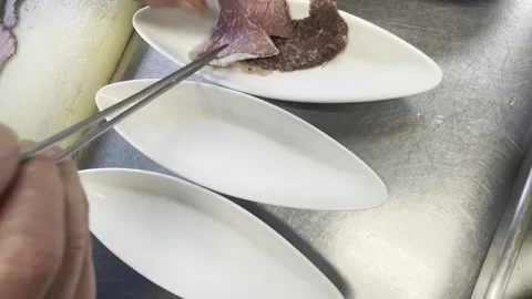 Chef Arranging Slices Of Roast Beef On White Plates In A Restaurant Kitchen Stock-Footage 338204040