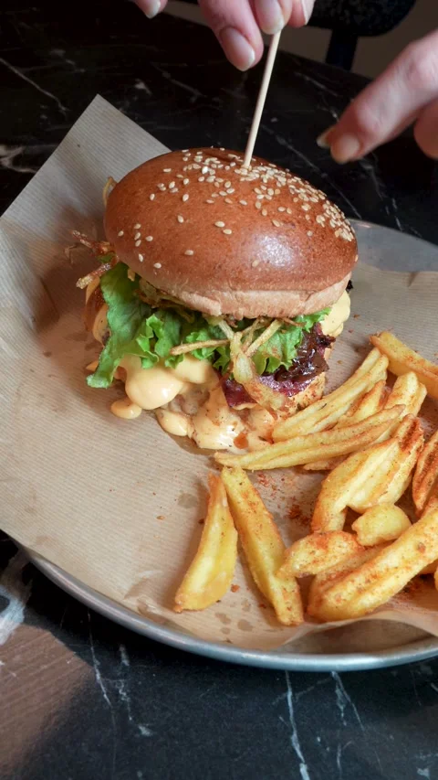 Chef Assembling Gourmet Burger with Skewer and Revealing Toppings Stock Footage 328459854