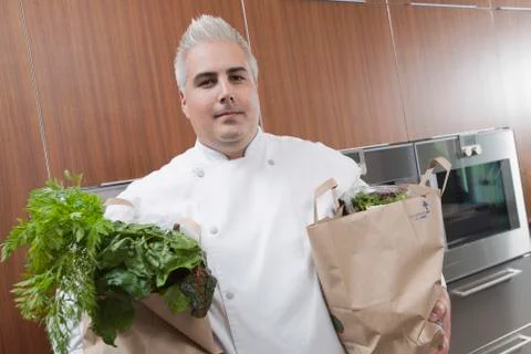 Chef With Bags Of Groceries In Commercial Kitchen Stock Photos