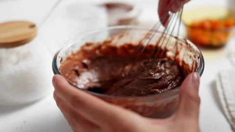 Chef, baker beating dough with a whisk on white kitchen table close-up. Fema Stock Footage 247363808