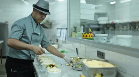 Chef baker decorating chocolate cake using sweet powder sweets and fruits Stock Footage 61943665