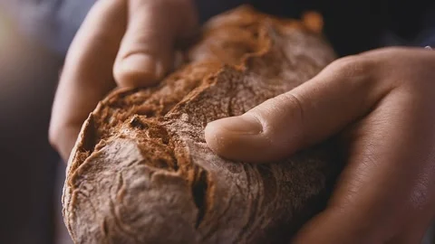 Chef Baker hold fresh handmade craft farm bread and shows it off in a sunny room Stock Footage
