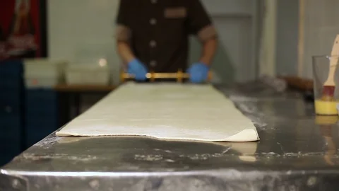 The chef in the bakery cuts the dough for cheese rolls Video stock 106475347