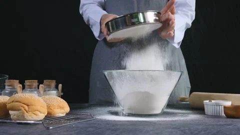 Chef bakery sifting flour through sieve into a bowl.Homemade bakery concept. Video stock 147088744