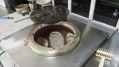 Chef baking naan bread in a tandoor oven at an Indian restaurant Stock Footage 304729792