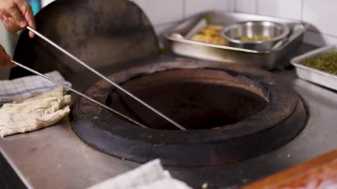 Chef Baking Naan Flatbread in Traditional Indian Clay Tandoor Oven Stock Footage 345792127