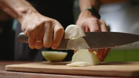 The chef in black apron cuts an onion with a knife Stock Footage 294540736