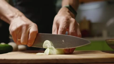 The chef in black apron cuts an onion with a knife Stock Footage 294540957