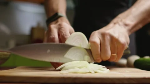 The chef in black apron cuts an onion with a knife Stock Footage 294540984