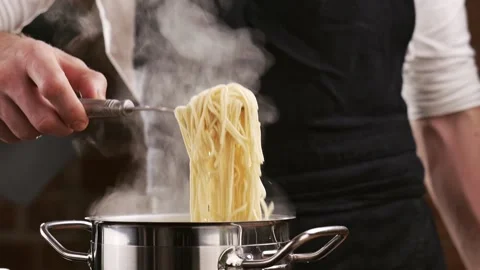 Chef in black apron get prepared pasta from boiling water. White smoke in slow Stock-Footage 151205540