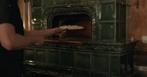 Chef in black apron, putting pizza in the wood-burning oven Stock Footage 201467855