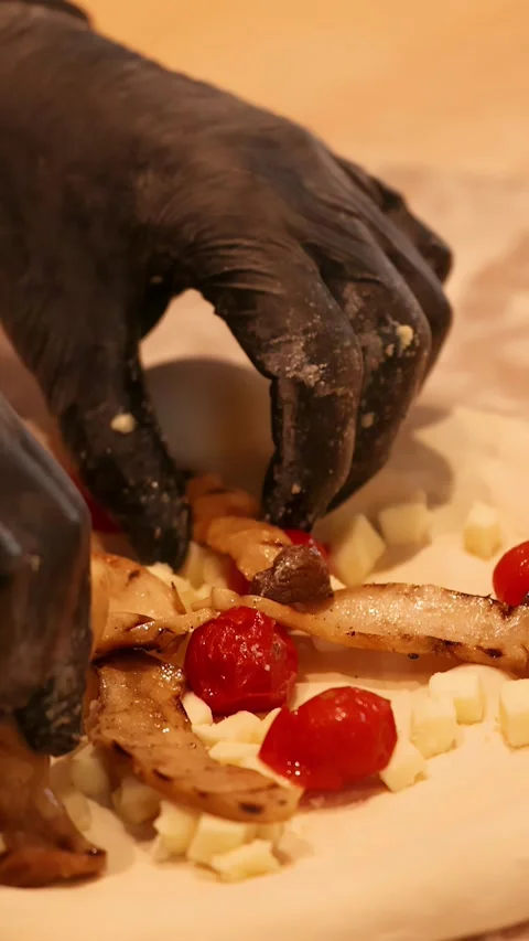 Chef in Black Gloves Adding Fresh Toppings to Raw Pizza Dough Stockbeeldmateriaal 337917970