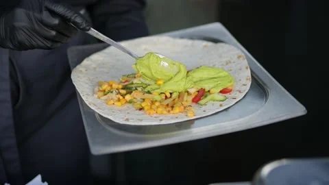 A chef in black gloves and a black jacket prepares tacos. Stock Footage 153047818