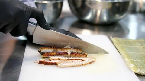 Chef in black gloves cuts pieces of eel fish for sushi with a large knife Vídeos de archivo 283554142