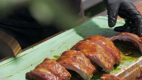 Chef with black gloves cutting freshly grilled ribs on green cutting board 動画素材 219775253