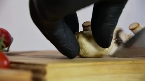 Chef in black gloves finely chop mushrooms in a pizzeria with a metal knife on  Stock Footage 135555434