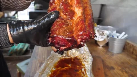 Chef in Black Gloves Holding a Large Rack of Glazed BBQ Pork Ribs, Close-up Stock Footage 338213791