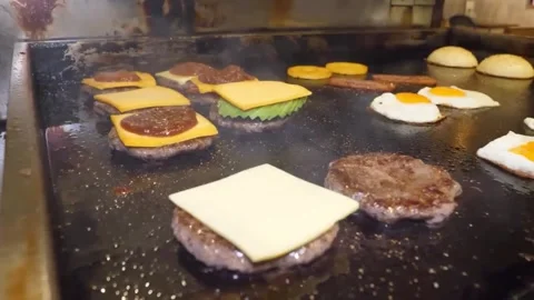 Chef in Black Gloves Placing Cheese Slices on Sizzling Burger Patties on Flat-To 스톡 동영상 347687650