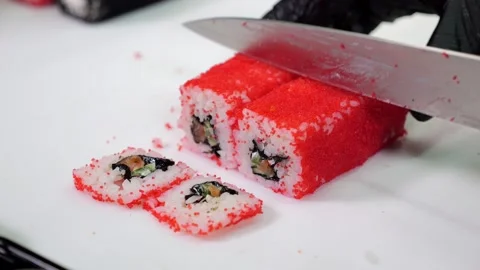 A chef in black gloves prepares sushi, he slices sushi with a large knife. Stock Footage 321814318