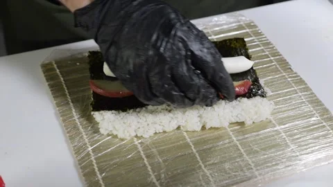 A chef in black gloves prepares sushi in the kitchen of a Japanese restaurant. Stock Footage 329403246