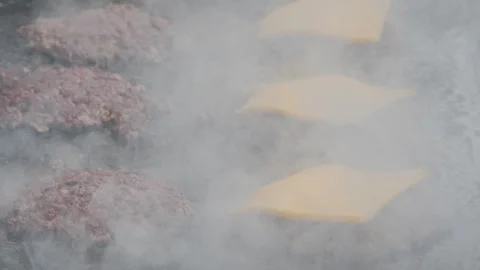 A chef in black gloves prepares a trendy smash burger on a flat griddle, close Stock Footage 306300754
