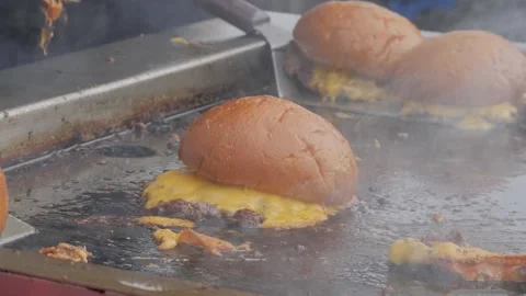 A chef in black gloves prepares a trendy smash burger on a flat griddle, close Stock Footage 306301190