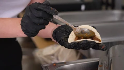 Chef in black gloves preparing a delicious homemade taco with meat and beans Stock Footage 346186604