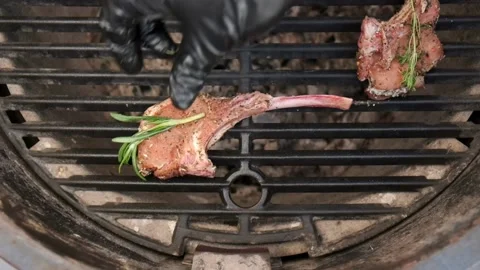 A chef in black gloves puts a bone-in steak on the grill. Camera movement. Stock Footage 139783023