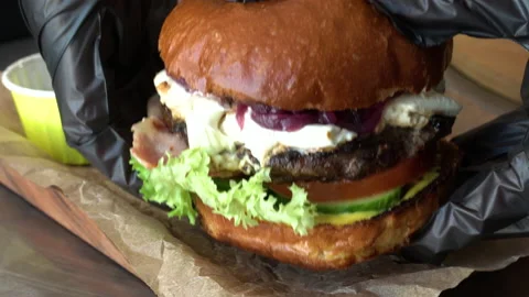 The chef in black gloves puts a burger on a board with rustic potatoes and sauce Stock Footage 179313672