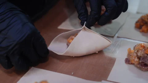 Chef in black gloves skillfully preparing dumplings Stockbeeldmateriaal 323097093