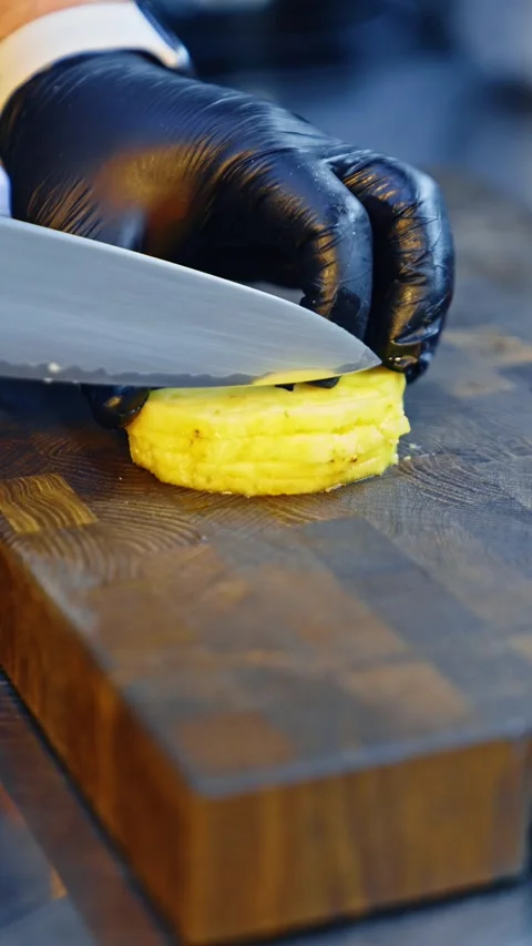 Chef in black gloves slicing fresh pineapple on wooden board with sharp kni.. 库存影片 337469110
