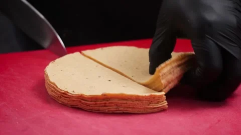 Chef in Black Gloves Slicing Stack of Corn Tortillas on Red Cutting Board Stock Footage 331634660