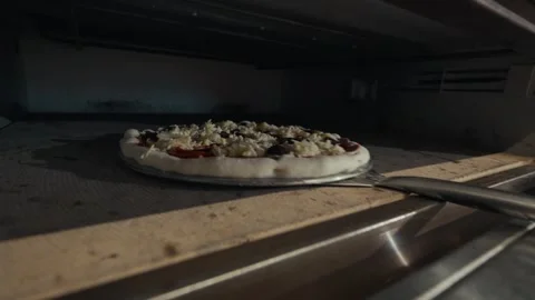 Chef in black gloves slides pizza into commercial oven, showcasing the cooking Vídeo Stock 332736593