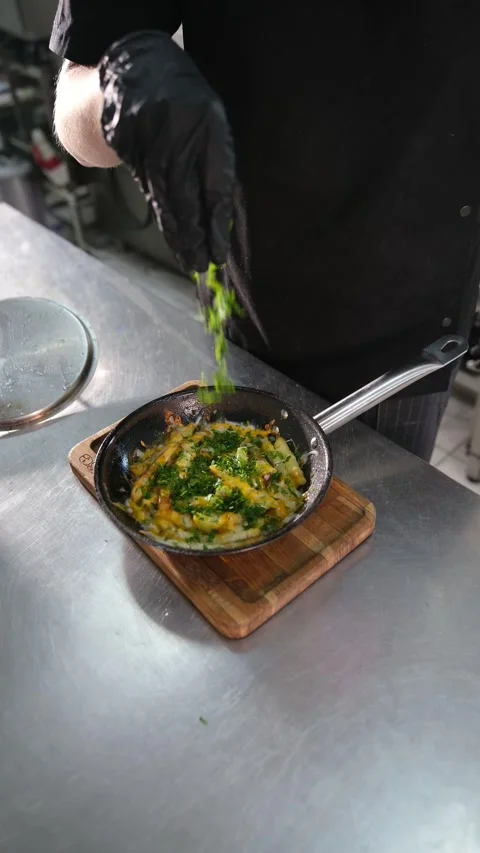 Chef in black gloves sprinkling chopped herbs over cheesy pan-fried potatoes Stock Footage 318317042
