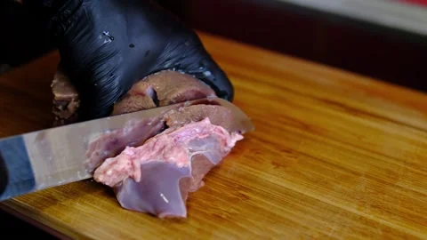 Chef in black gloves trimming connective tissue from fresh raw beef liver on Stock Footage 346264935