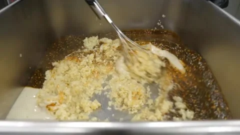 Chef in black gloves using a wire whisk to mix minced garlic, oil, and liquid se Video stock 343028402