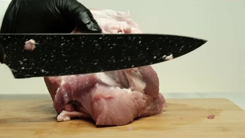 Chef in black protective gloves cuts and prepares raw pork for cooking. Stock Footage 153434456