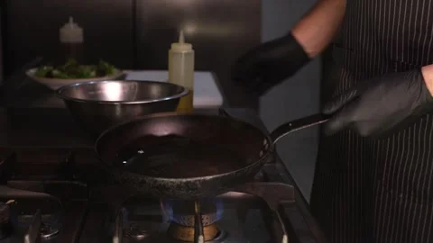 Chef in black rubber gloves heating pan with oil before cooking shrimp in profes Stock Footage 334126614