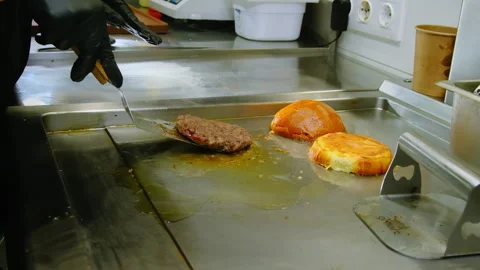Chef in black rubber gloves uses spatula to flip sizzling patty Stock-Footage 324922841