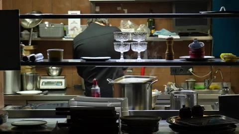 A chef in a black uniform is preparing something in a professional open kitchen Stock Footage 303473129